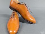 pair of men ' s tan leather shoes with laces on a gray surface