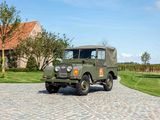 a green jeep parked on a cobblestone road in front of a house