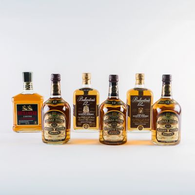 quatre bouteilles de whisky alignées sur une surface blanche