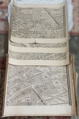 a person holding a stack of old maps on a table