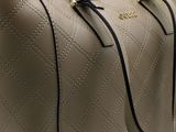 a close up of a tan purse with a black handle