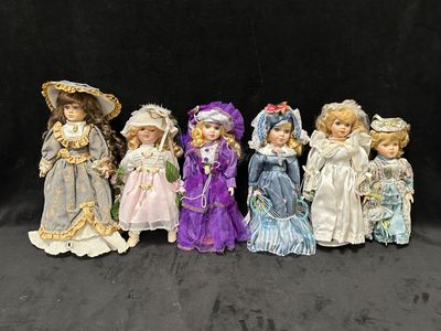 sept poupées en porcelaine de différentes couleurs et tailles sur un fond noir