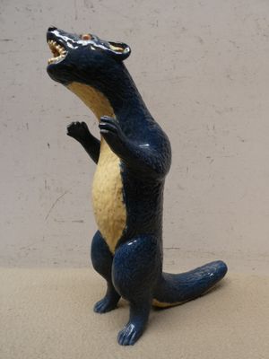 une statue bleue et jaune représentant un lézard, posée sur une surface beige clair