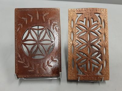 une paire de portefeuilles en cuir ornés de motifs complexes, exposés