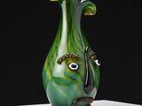 a green vase with a face on it sitting on a table