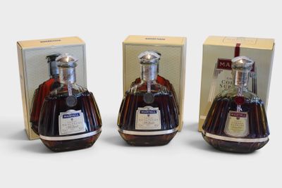 three bottles of brandy sitting next to each other on a white surface