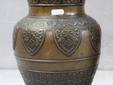 a bronze vase that is sitting on a white surface