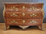 an antique chest of drawers with a marble top on a wooden floor