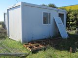 a small white building in the middle of a grassy field