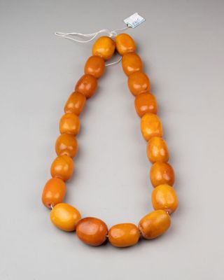 a close up of a necklace with orange beads on a gray surface