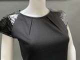 a mannequin wearing a black dress with sequins on the shoulders