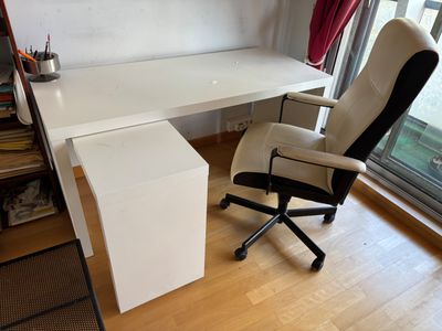 un bureau blanc avec une chaise noire devant une fenêtre