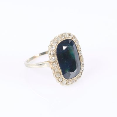 a close up of a ring with a blue stone surrounded by diamonds