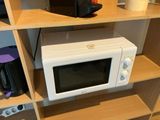 a microwave sitting on a shelf in the corner of a room