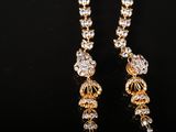 a pair of gold and diamond earrings on a black surface
