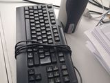a computer keyboard and a cup of coffee on a desk