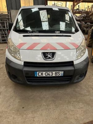 l'avant d'une camionnette blanche garée dans un garage, à côté d'un tas de pneus
