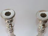 two silver candlesticks sitting on a white table