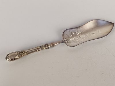 cuillère de service plaquée argent avec un manche ouvragé sur fond blanc