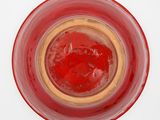 a glass with a red substance in it on a white surface