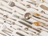 many spoons and forks laid out on a white surface