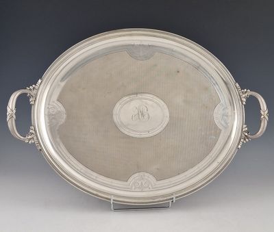 une assiette en argent ancienne avec des poignées et des poignées sur un support