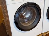 two washers and a dryer stacked on pallets