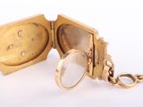 a gold pocket watch with a keychain on a white surface