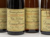 four bottles of wine are lined up on a white surface