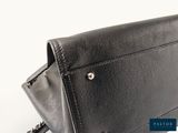the back of a black leather purse with a chain hanging from it