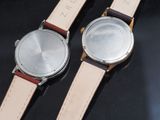 two watches sitting side by side on a black surface