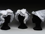 trois têtes de mannequins noires ornées de dentelle blanche et de nœuds