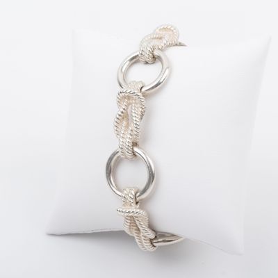 a close up of a silver bracelet on a white pillow