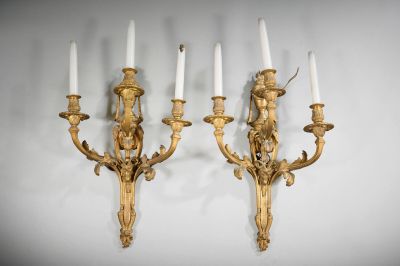 pair of gilded wall sconces with candles on each of them
