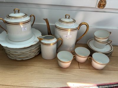 beaucoup d'assiettes et de tasses blanches et dorées sur la table