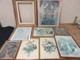 many framed pictures on a table with a vase of flowers