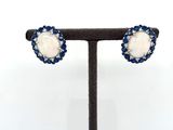 a pair of blue and white stone earrings on a black stand