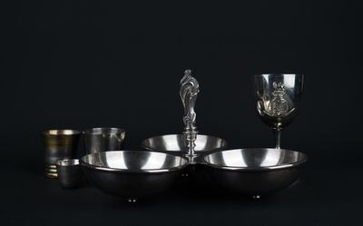 trois bols en argent et un verre à vin posés sur une table noire