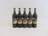 quatre bouteilles de vin sont alignées sur une surface blanche