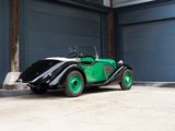 a green and black car parked in front of a garage