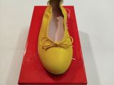 des ballerines dans une boîte posée sur une surface blanche, avec une boîte rouge à côté