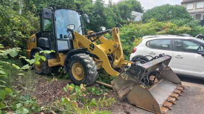 a bulldozer that is parked next to a white car