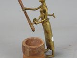 bronze figurine of a woman holding a baseball bat next to a clay pot