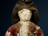 a small doll that is wearing a hat and a jacket