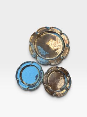 three blue and gold ashtrays on a white surface