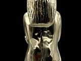 a silver sculpture of a woman sitting on a chair