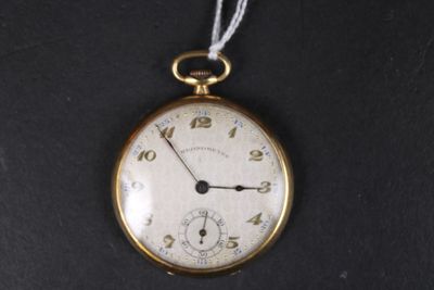 une montre de poche en or suspendue à un cordon sur une surface noire