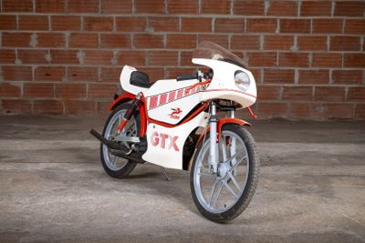 a white and red motorcycle parked in front of a brick wall