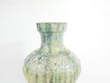 a green vase that is sitting on a white surface