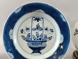 a blue and white plate sitting next to a white and blue vase